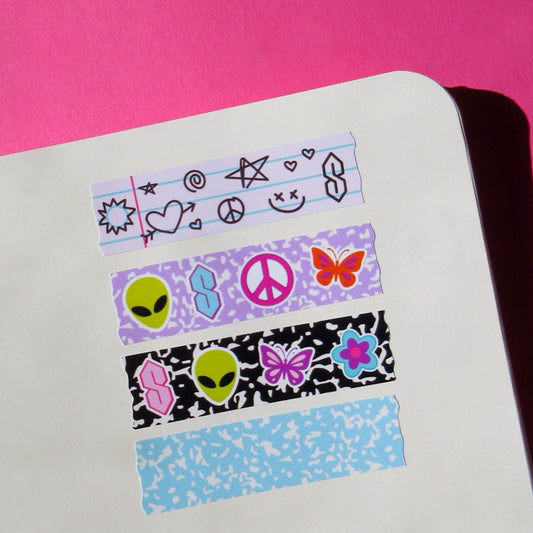 Four strips of decorative washi tape stickers with retro y2k themed designs, including aliens, peace signs, butterflies, and stars, arranged on a white notebook page against a bright pink background.