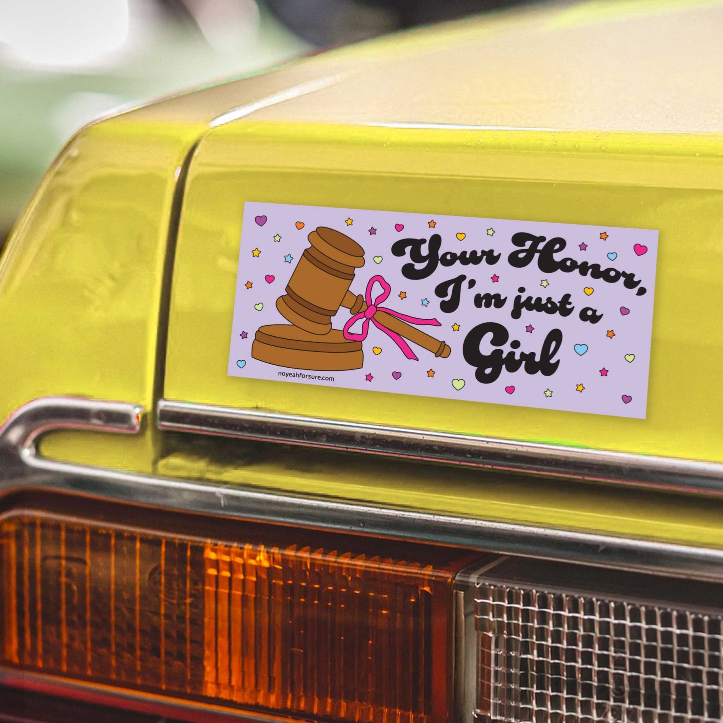 Bumper sticker with a gavel and text on a yellow car's rear bumper