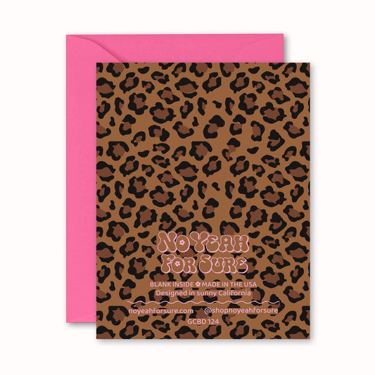The back side of a leopard print greeting card with a pink envelope behind it.