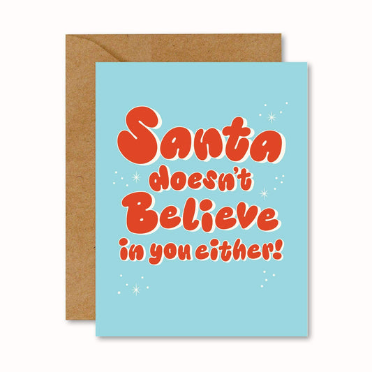 Greeting card with 'Santa doesn't believe in you either!' bubbly font text on a blue background with a brown envelope.