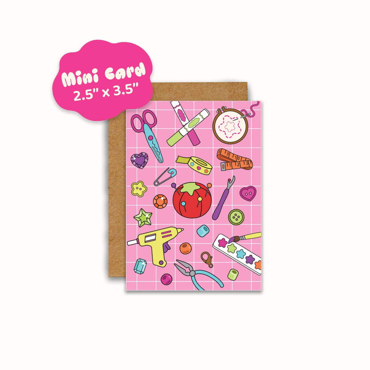 A pink mini card with a grid pattern and colorful craft themed illustrations, shown with a brown kraft envelope. A pink cloud shaped label in the top left reads 'Mini Card 2.5" x 3.5".