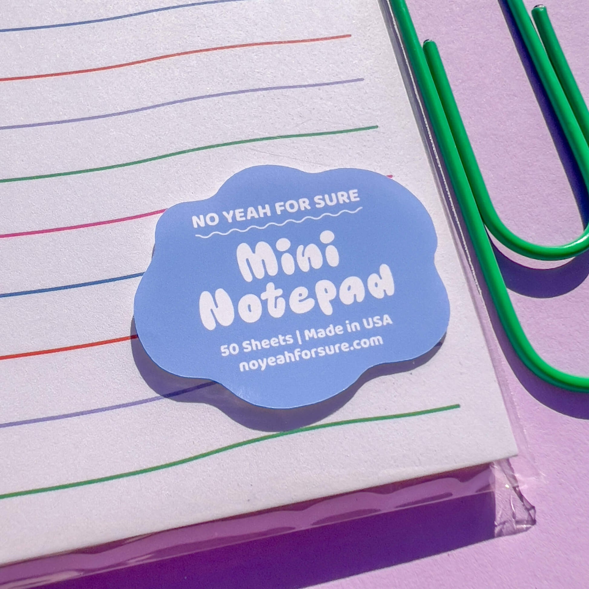Mini notepad with colorful lines and a blue label on a purple background