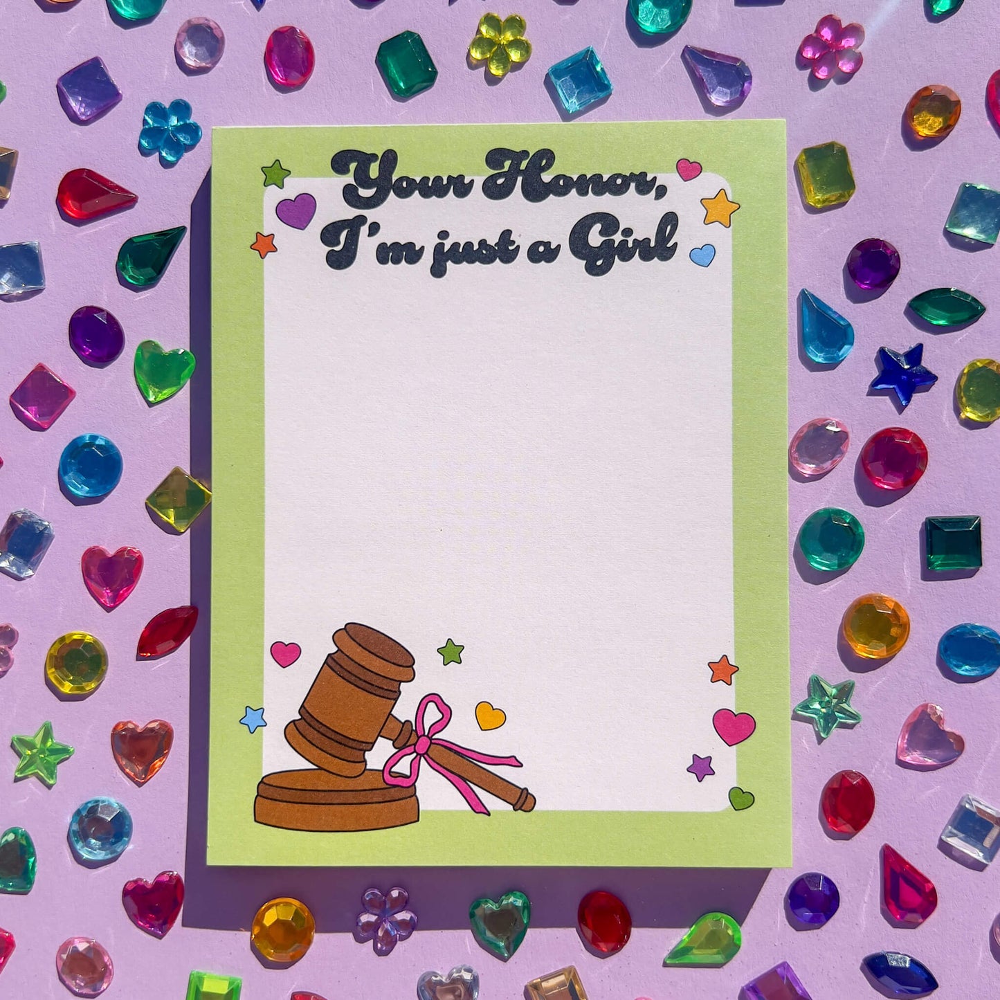Notepad with gavel illustration and text 'Your Honor, I'm just a girl' on a colorful gemstone background