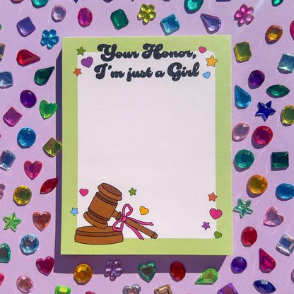 Notepad with gavel illustration and text 'Your Honor, I'm just a girl' on a colorful gemstone background