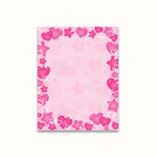 A notepad with a decorative border of airbrush hearts and stars in various shades of pink and white, set against a light off-white background.