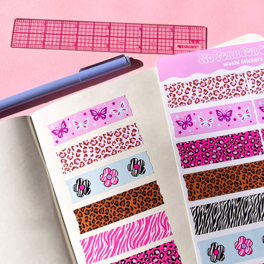A sheet of washi stickers displayed on an open notebook, alongside a pink ruler and a purple pen. The stickers feature various patterns including leopard print, zebra print, butterflies, and flowers in multiple colorways.
